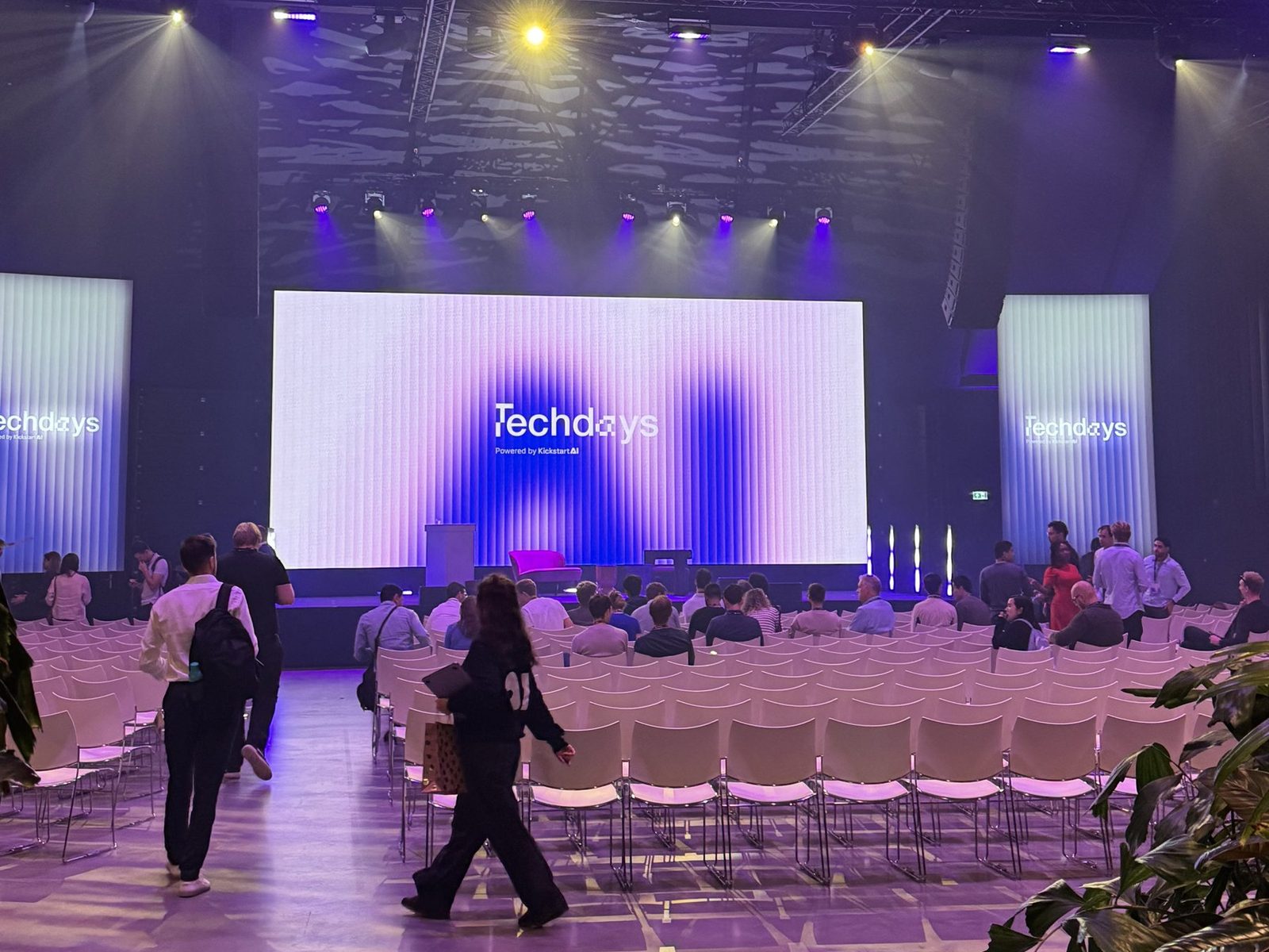 The main hall at Circa: a large screen reading Techdays above the stage, rows of white chairs, and people walking to their seats.